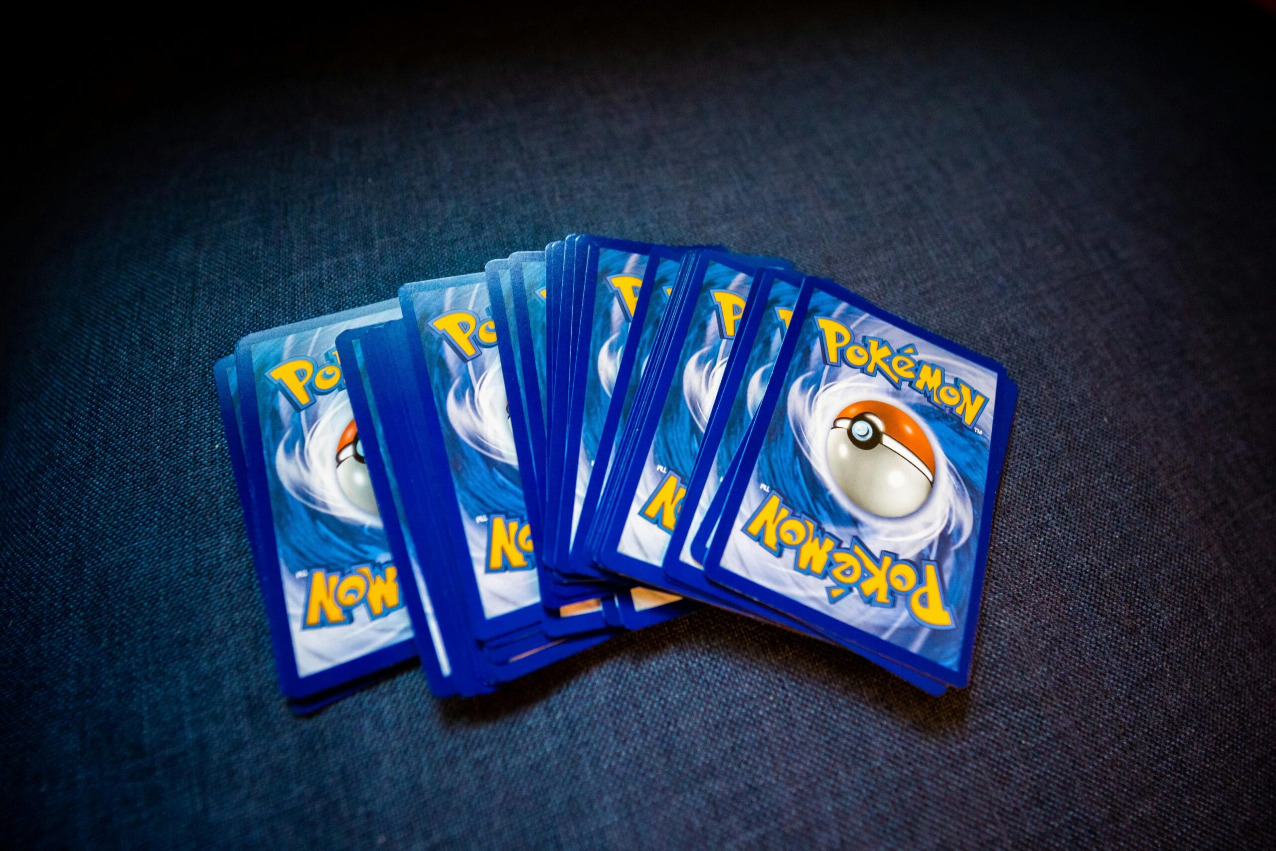 A collection of Pokemon trading cards laid out on a dark surface showcasing their distinct back designs