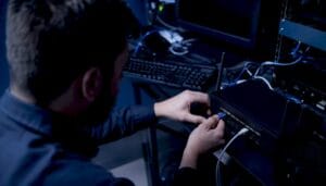 Technician connecting Ethernet cable to a network switch in a server rack