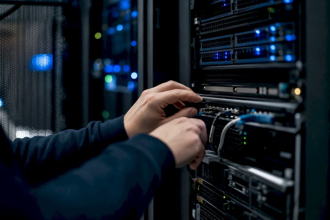 Mains réglant un switch réseau dans une salle serveur cloud